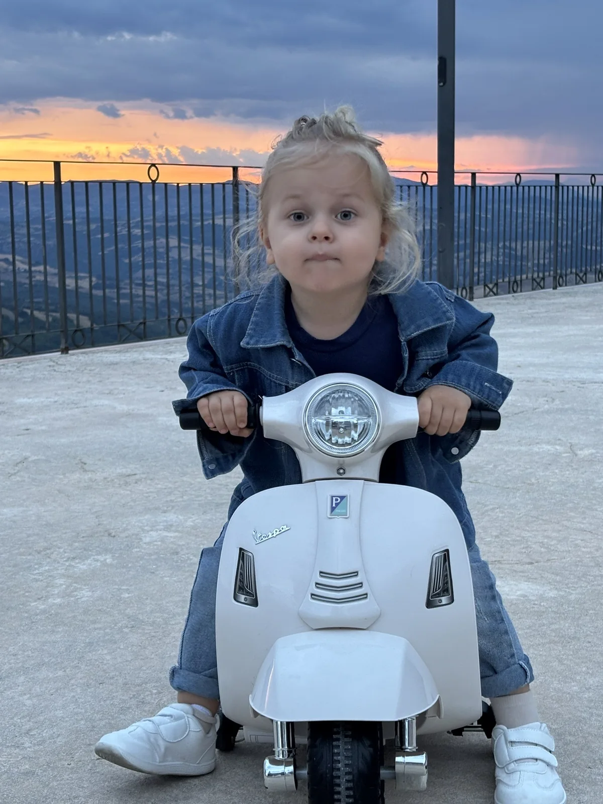 Theo su una piccola Vespa davanti a un paesaggio italiano